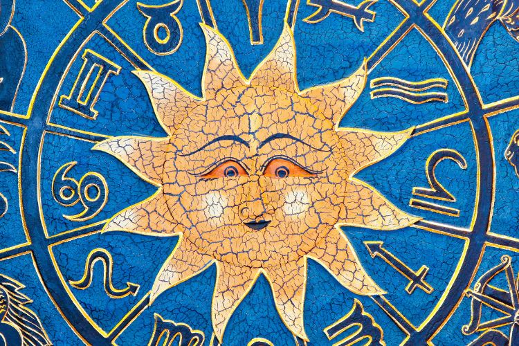 A imagem apresenta um sol estilizado no centro, com um rosto sorridente e traços detalhados, cercado pelos símbolos do zodíaco em um fundo azul vibrante. As cores e texturas remetem a um estilo artístico clássico e místico.