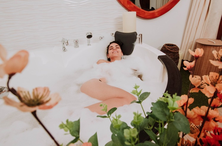 mulher tomando banho de banheira com muitas flores ao redor