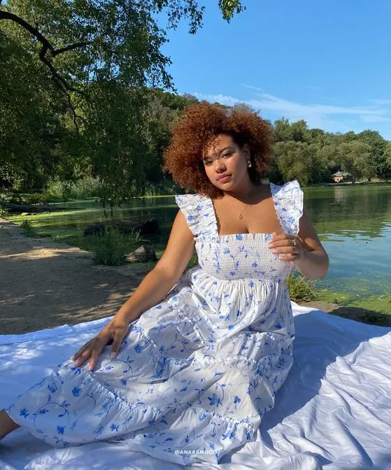 Vestido cottagecore puls size, modelo sentada em tecido ao ar livre