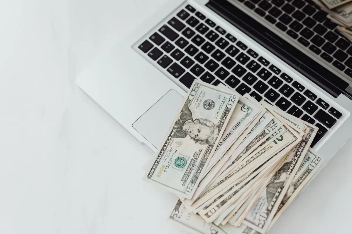 Notas de dinheiro sobre notebook representando solicitação de crédito digital e empréstimo online em 2026.
