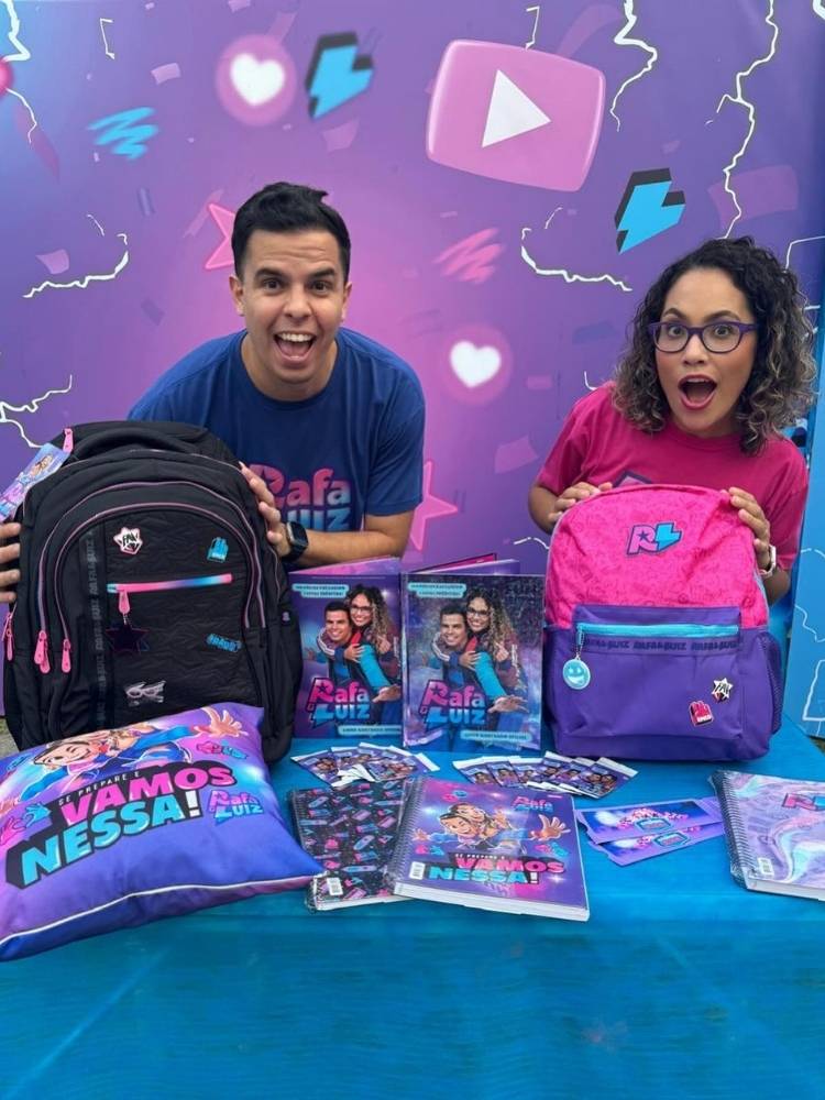 Rafa e Luiz em stand com produtos licenciados de sua marca, como mochilas e almofadas