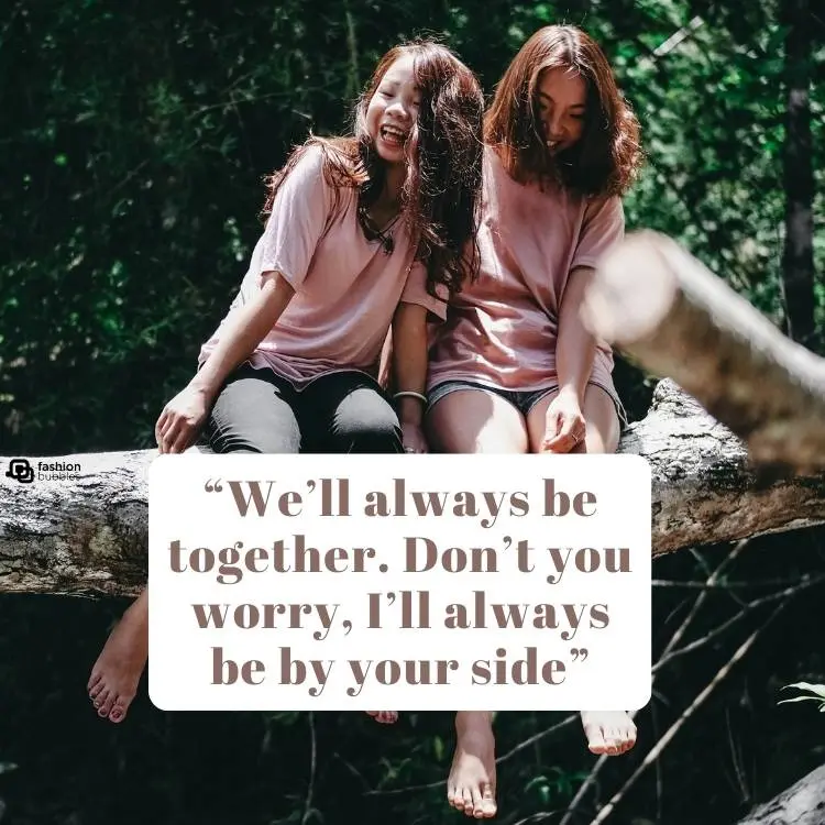 A imagem mostra duas jovens amigas orientais usando blusa rosa clara, uma delas de calça preta e a outra de shorts jeans. Ambas estão sentadas sobre um tronco, com árvores ao fundo. Em cima do tronco, há um bloco bege com o trecho "We’ll always be together. Don’t you worry, I’ll always be by your side".