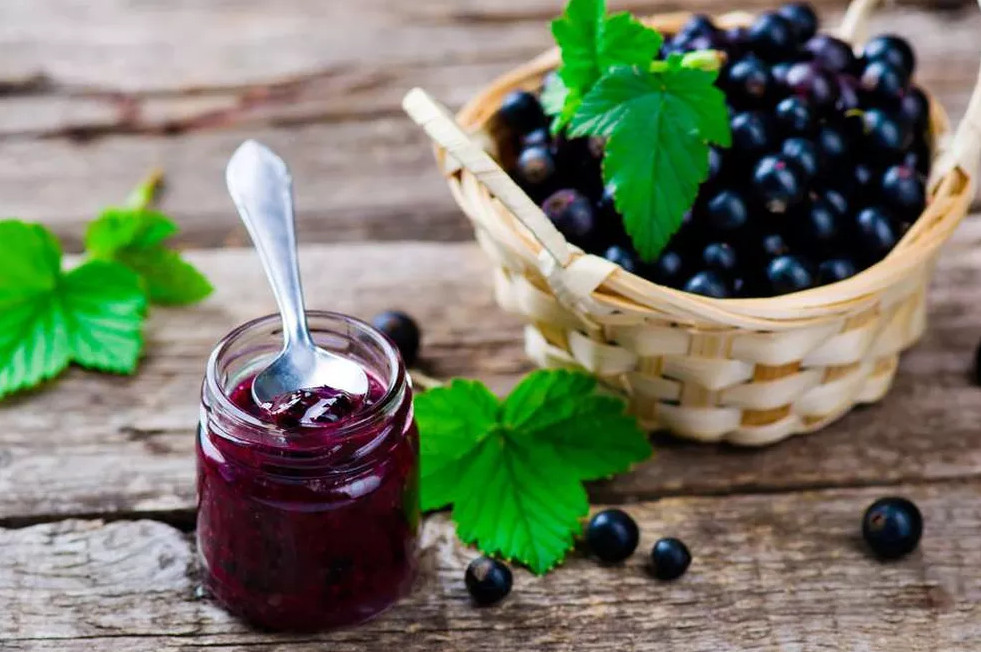 Foto de pote geleia de jabuticaba com colher e frutos de jaboticaba ao lado Receita de geleia de jabuticaba
