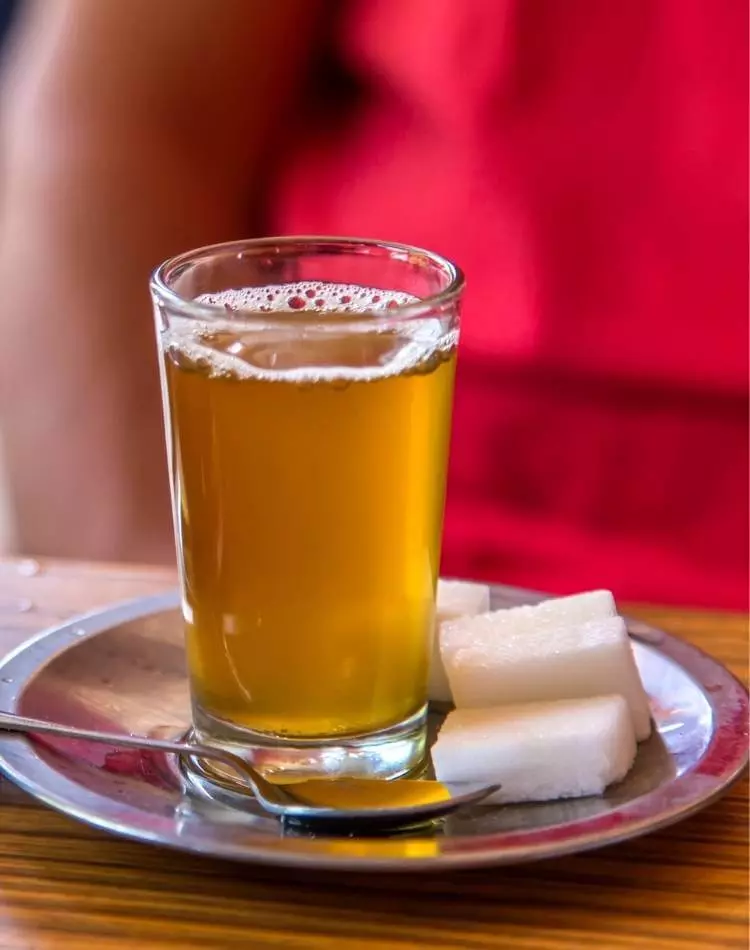 Copo com chá de arruda e cubos de açúcar.