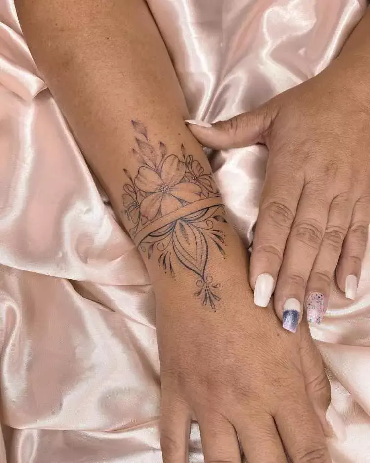 tatuagem na parte superior do pulso com flores e arabescos