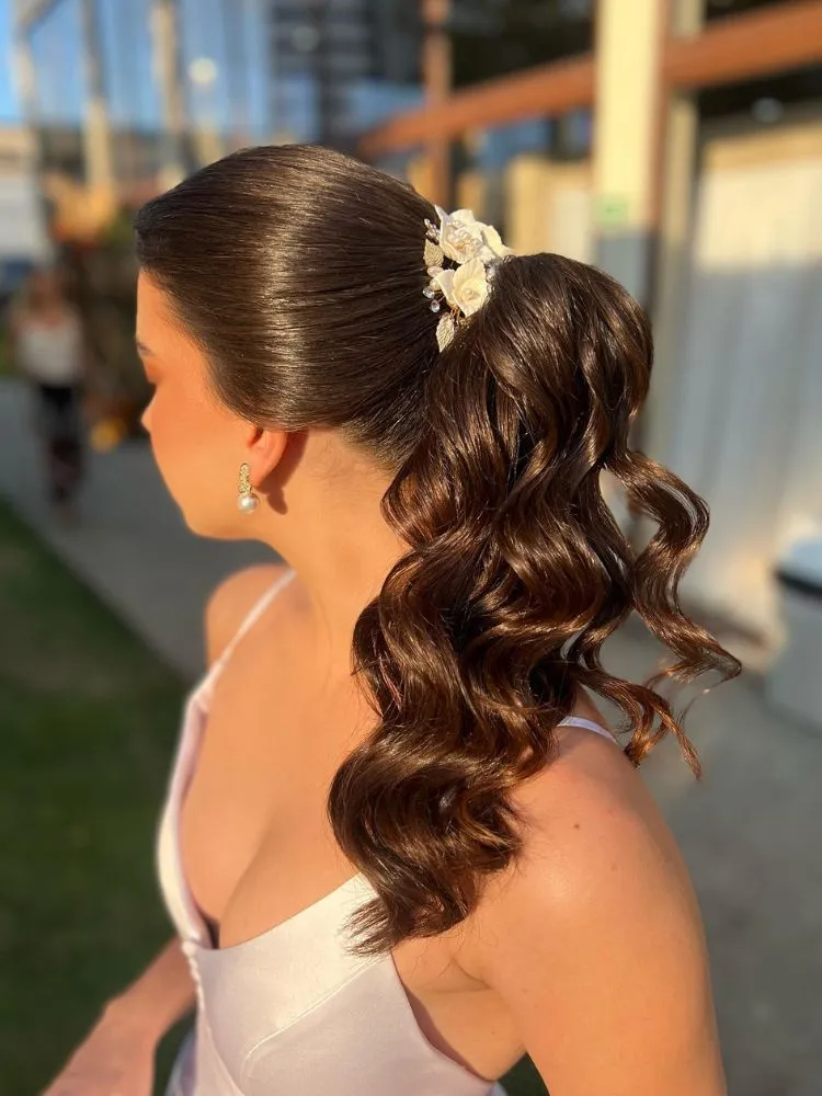 Noiva de pele clara usando vestido branco slim decotado e cabelo preto em rabo de cavalo com flores brancas