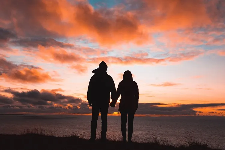 casal de mãos dadas no pôr do sol