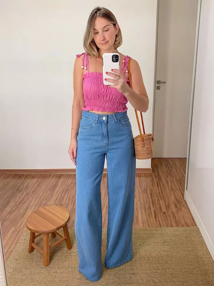 Mulher de pele clara com calça jeans wide leg e cropped rosa
