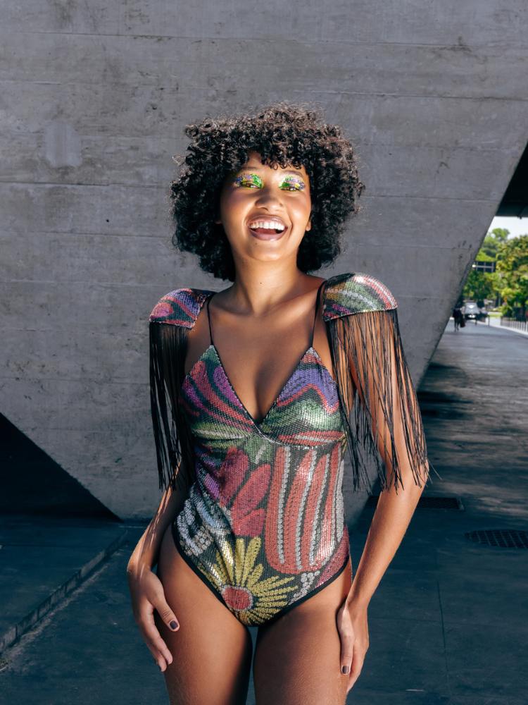Mulher de pele negra com body colorido e ombreira de franja 