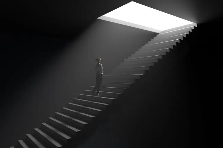 Pessoa solitária subindo uma longa escada em direção a uma abertura iluminada em um ambiente escuro. A imagem simboliza superação, esperança e a busca por oportunidades em meio a desafios, com foco na persistência e resiliência.
