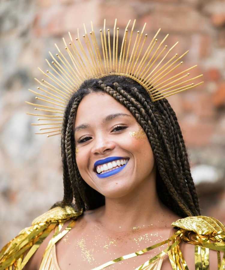 Mulher sorridente com fantasia e tiara de sol para o Carnaval.
