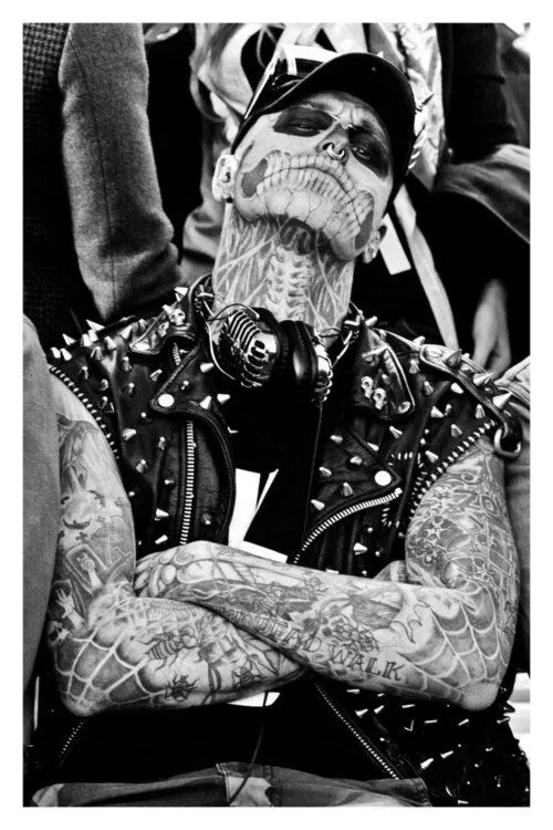 Foto em preto e branco de homem maquiado de caveira e com tatuagem no pescoço 