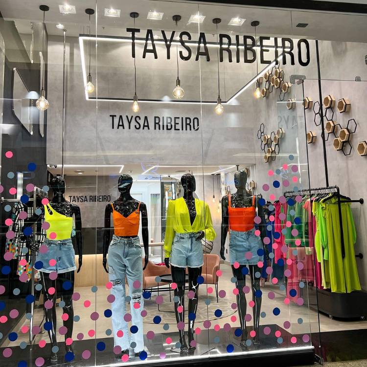 Vitrine de loja de roupas com bolinhas em tons de azul e rosa coladas no vidro. 