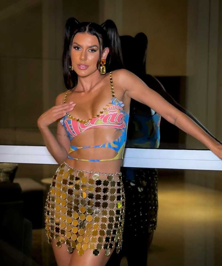 Mulher de pele clara usando abadá customizado cut out com lantejoulas grandes douradas e saia vazada dourada