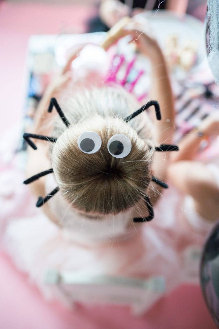 Criança loira com coque de aranha, com pernas e olhos 