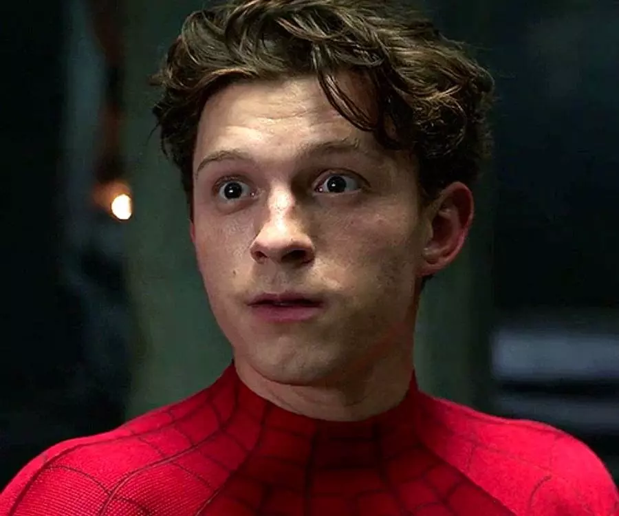 Rosto espantadodo ator Tom Holland em cena como Homem-Aranha. Ele está usando a roupa do herói.