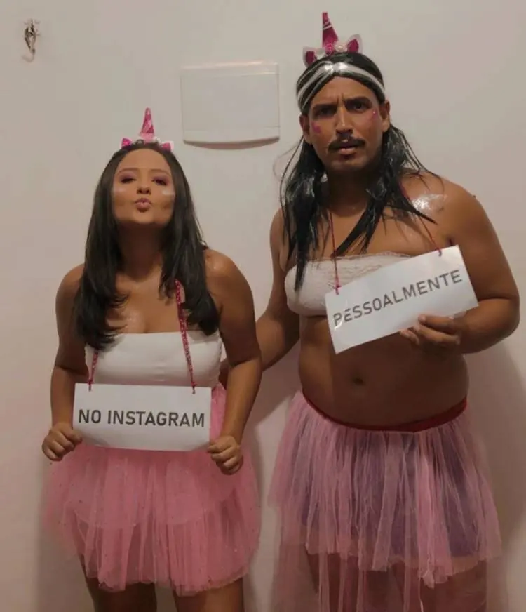 Mulher e homem fantasiados de top branco e saia de tule, mas a mulher usa placa "no Instagram" e ele "pessoalmente"