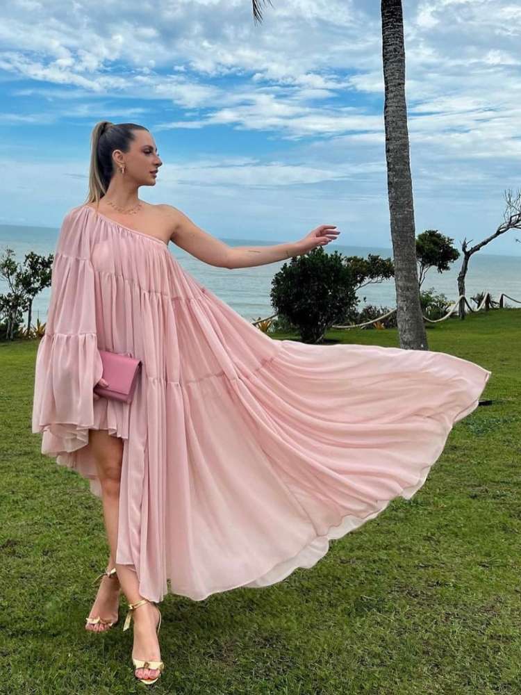Mulher de pele clara em casamento na praia usando vestido fluido rosa claro