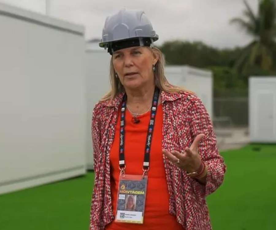 Ingrid Berger fotografada da cabeça a cintura. Usando crachá do Rock in Rio, está em gramado verde com paredes brancas no fundo.