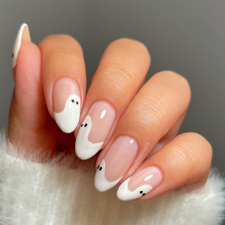 Mão com unhas longas amendoadas decoradas com fantasmas simples, nas cores branco transparente, branco e preto