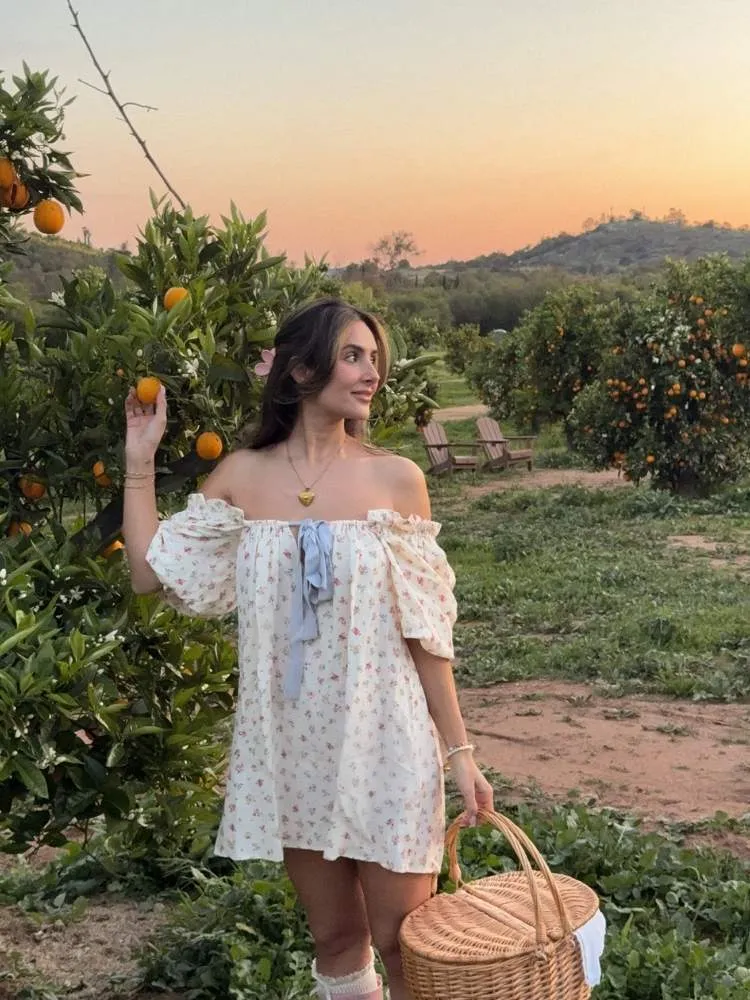 Mulher de pele clara com vestido curto ombro a ombro com manga bufante 