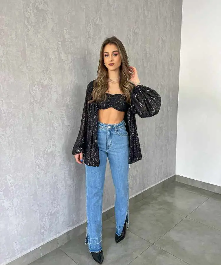 Mulher com top e casaco brilhosos + calça jeans.