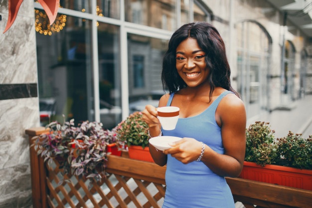 Mulher tomando chá em uma xícara e sorrindo