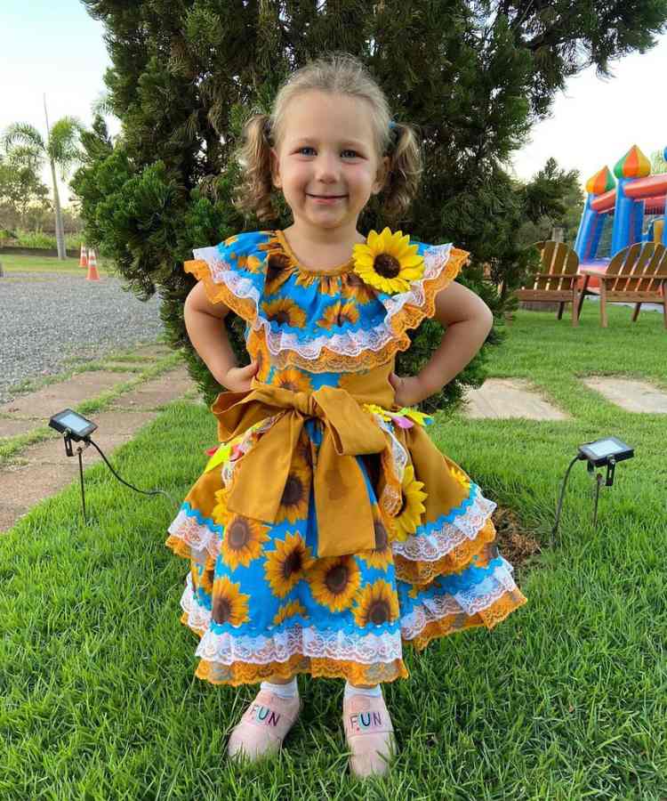 Menina com vestido de festa junina estampa girassol, babados