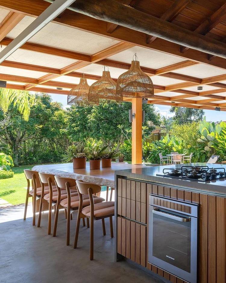 Mesa de pedra com banquetas e ilha com fogão em uma cozinha na roça