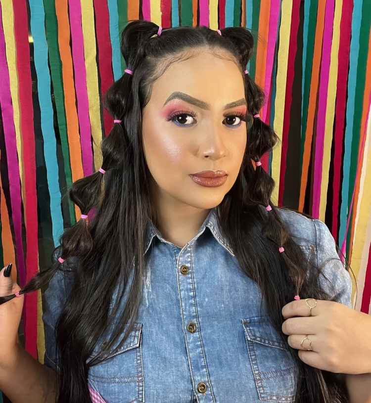 mulher com maquiagem nos olhos rosa e tranças no cabelo