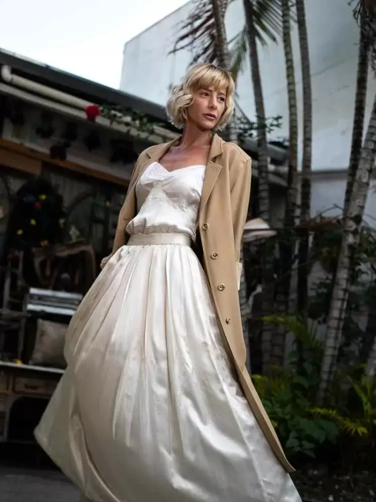 Mulher não-modelo com mais de 50 anos em ensaio fotográfico, usando vestido estilo de noiva, com blazer bege