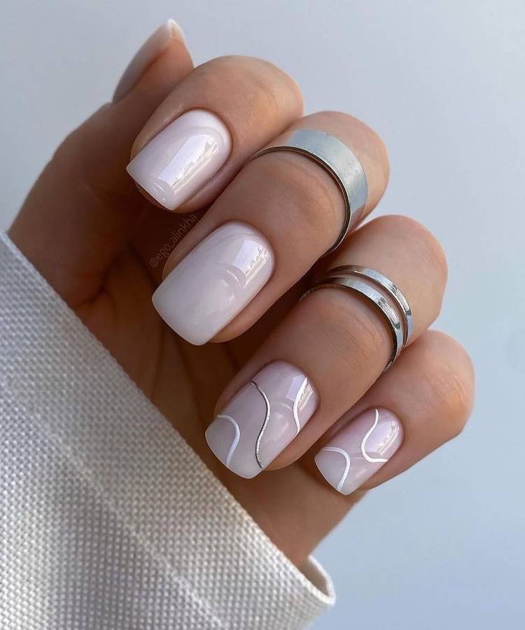 Unhas em formato amendoado decoradas com esmalte nude rosado e desenhos delicados de margaridas brancas com miolo amarelo. O acabamento minimalista e artístico destaca sofisticação e frescor. Fundo branco com textura suave complementa a elegância do design floral.





