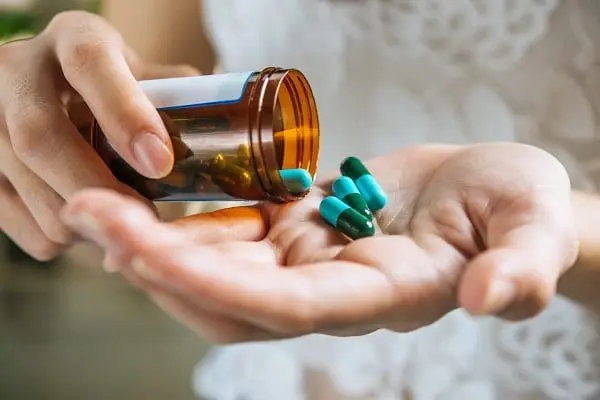 Foto de mãos com vidro de remédio e capsulas de comprimidos na palma das mão nas mãos - Infecção urinária