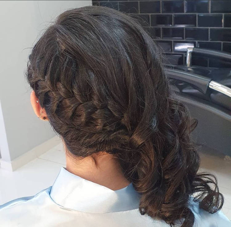 Mulher de costas com cabelo preto cacheado em trança lateral