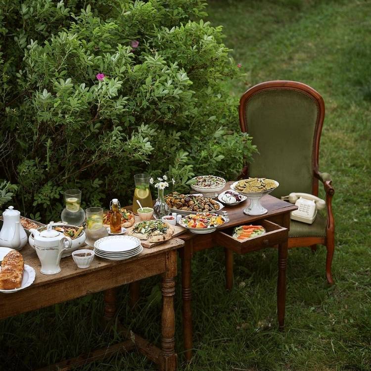Mesa posta ao ar livre, com comidas de brunch e cadeira de madeira