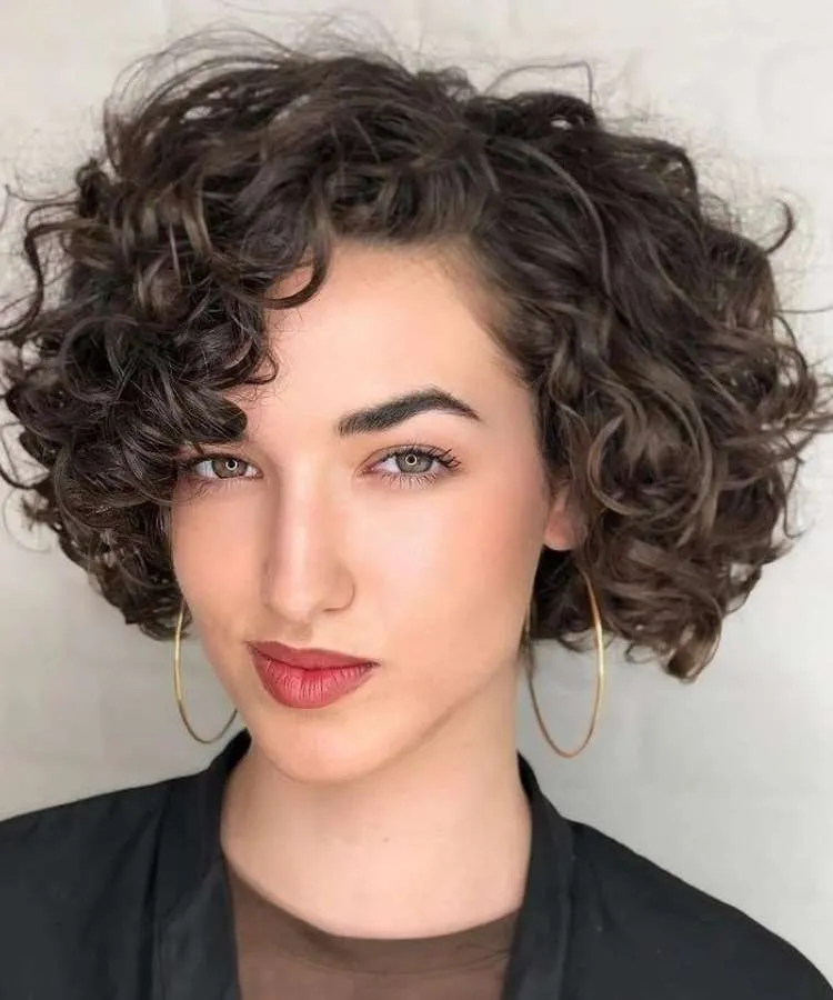 Mulher com cabelo curto cacheado e repicado usando blazer preto