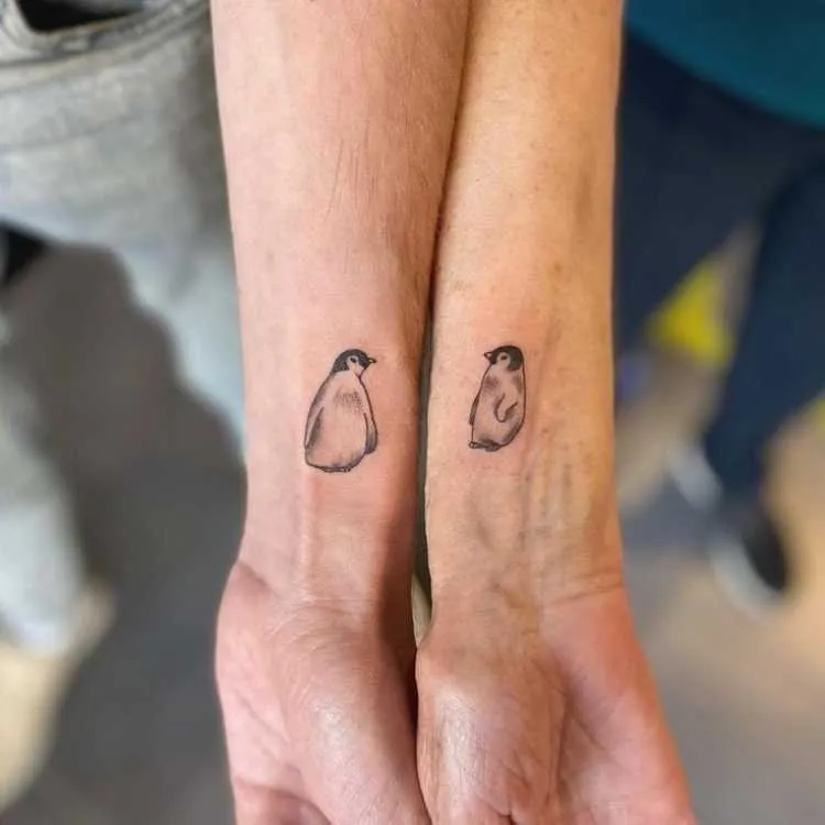 tatuagem mãe e filho no braço, cada um com um pinguim 