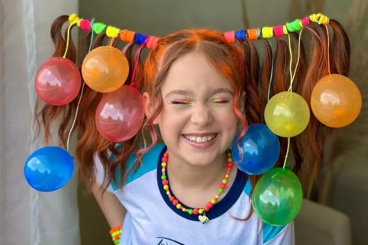 Foto de menina com elásticos coloridos e bexigas no penteado
