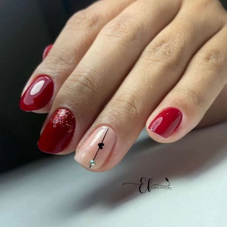 Nail art com vermelho escuro. glitter, nude, adesivo preto de coração e pedraria