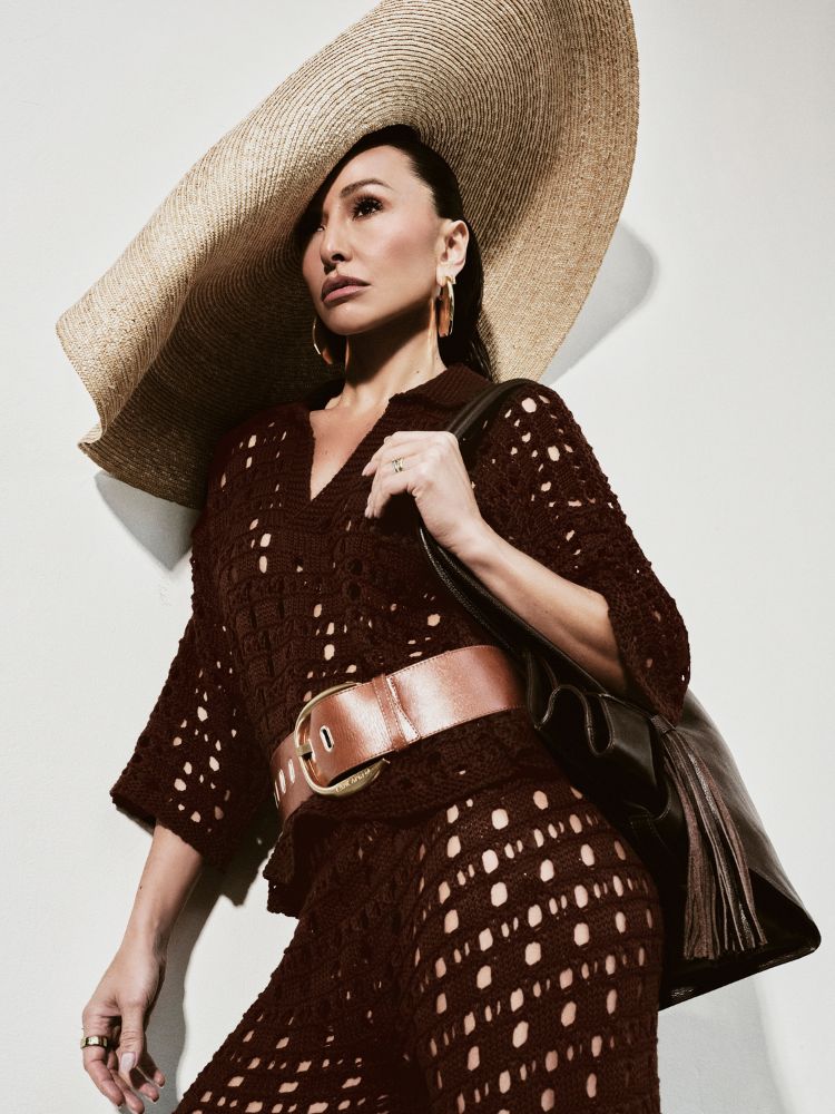 Sabrina Sato usando maxi chapéus e conjunto de tricô marrom com cinto dourado e bolsa marrom com detalhe de franjas 