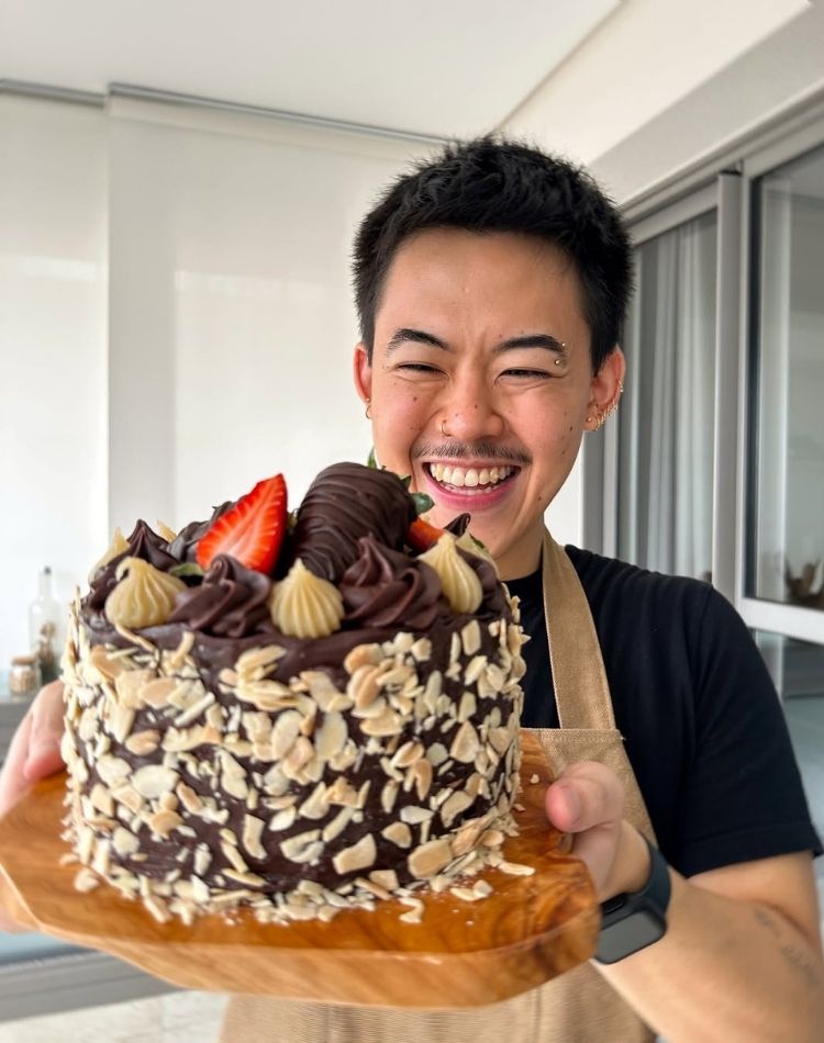 Foto de Leo Kazuya segurando um bolo vegano de chocolate branco e preto com morangos