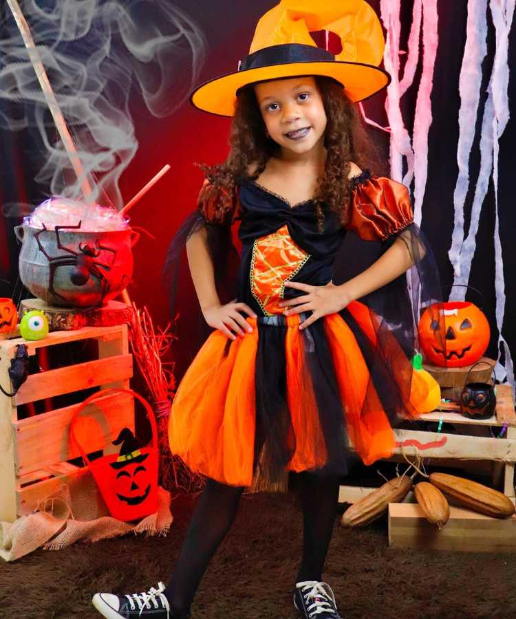 Garota fantasiada para o Halloween: Cores predominantes:preto e abóbora . Usa: vestido, meia calça, tênis, chapéu pontudo