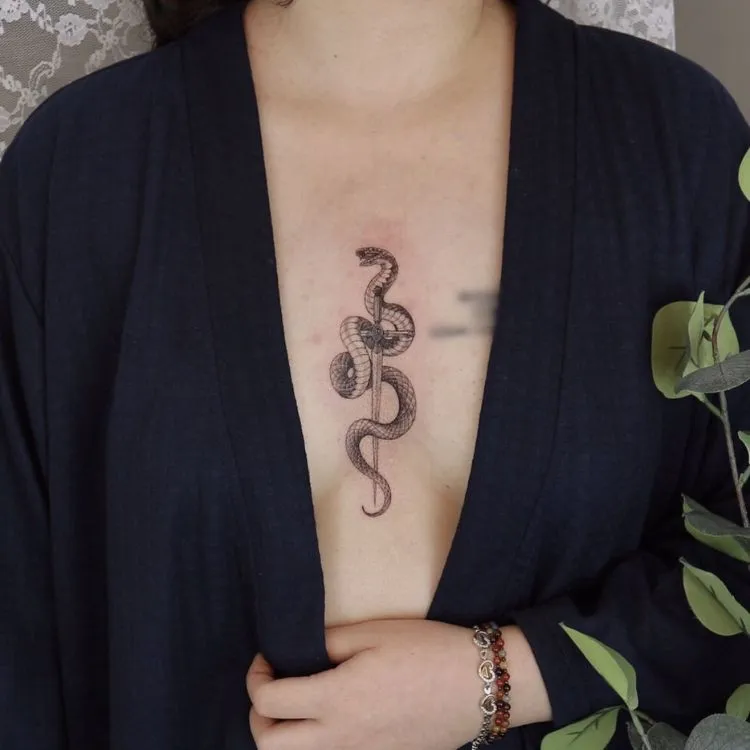 uma mulher com uma tatuagem entre os seios com uma espada e uma cobra