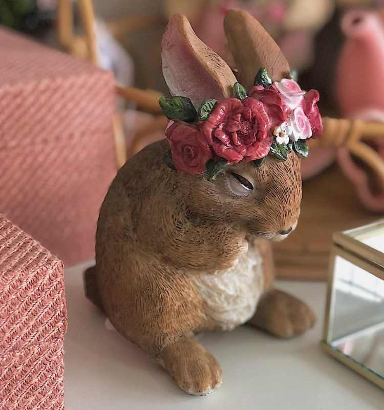 Coelho de cerâmica com coroa de flores.