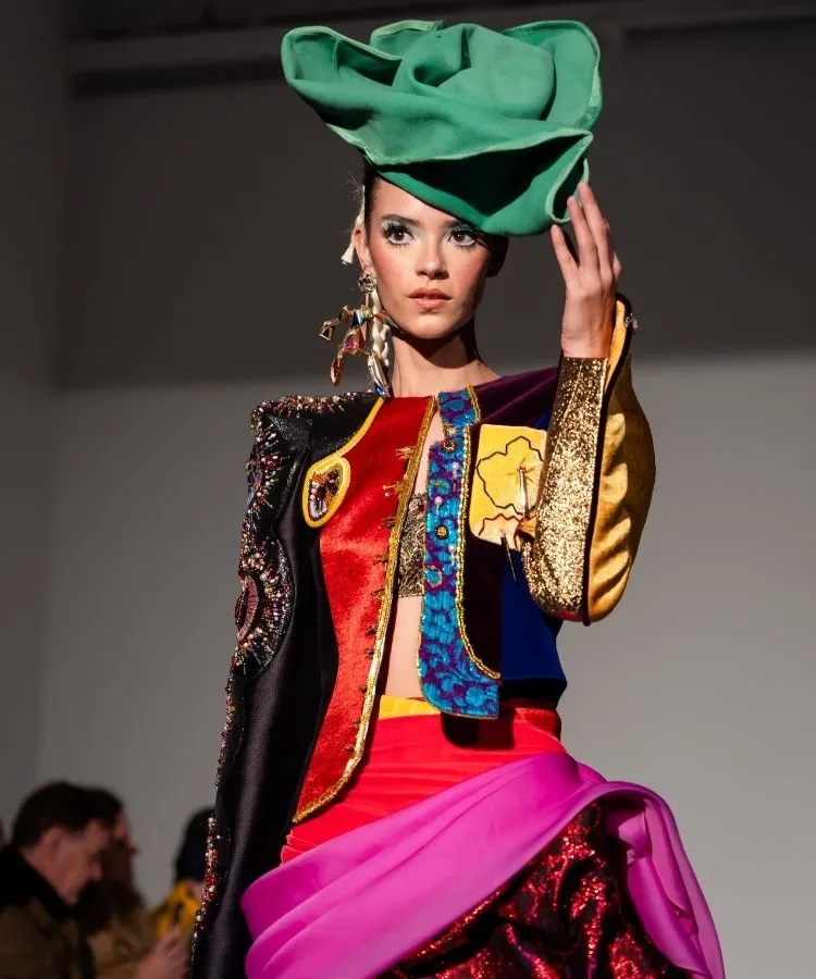 Modelo usando chapéu verde e look colorido no desfile de Thayná Caiçara na Semana de Alta-Costura de Paris 2026