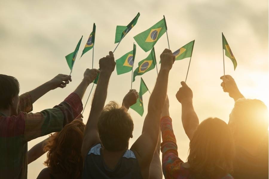 pessoas segurando bandeirinhas do Brasil, simbolizando 1ual é a atual situação política
