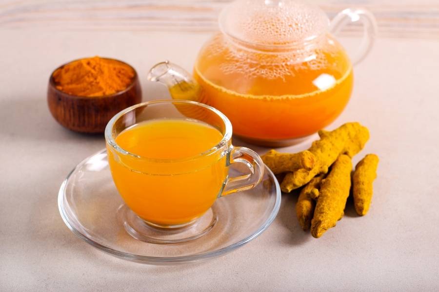 Xícara e bule com a infusão de açafrão.