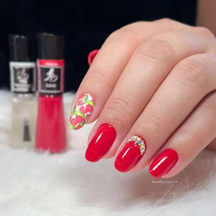 Unhas vermelhas decoradas co,m pedraria e adesivo de tulipas