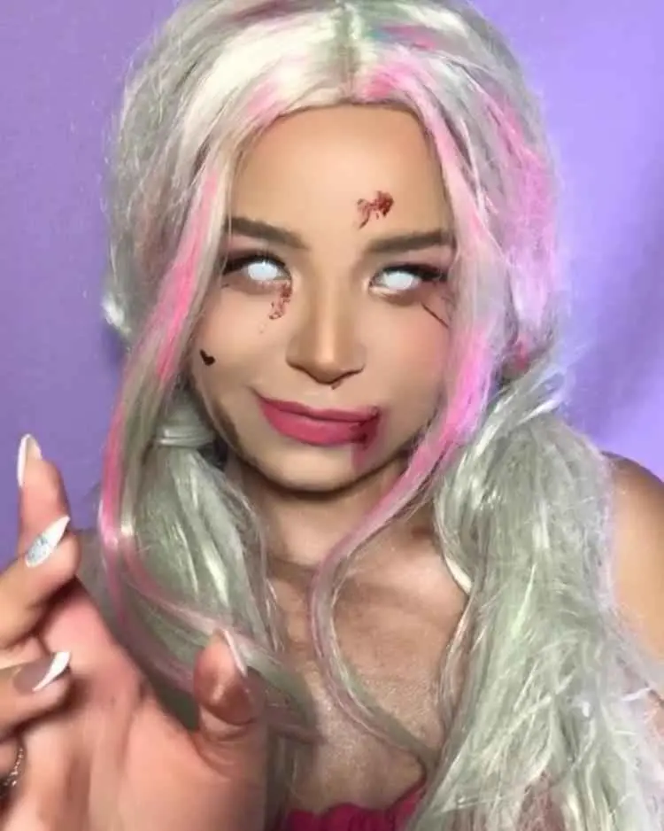 Mulher de pele clara com cabelo branco e rosa, sangue falso no rosto e lentes de contato brancas