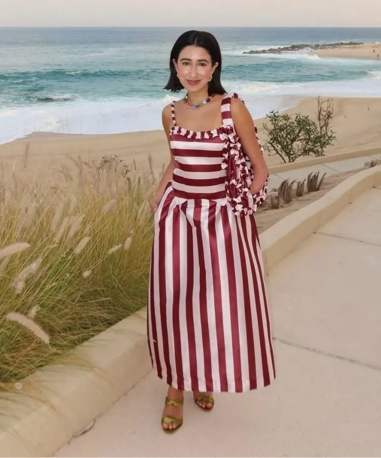 Foto da influencer April Lockhart usando vestido vermelho para o Natal listrado na praia